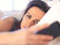Nešťastná žena v posteli, díval se na její mobilní telefon